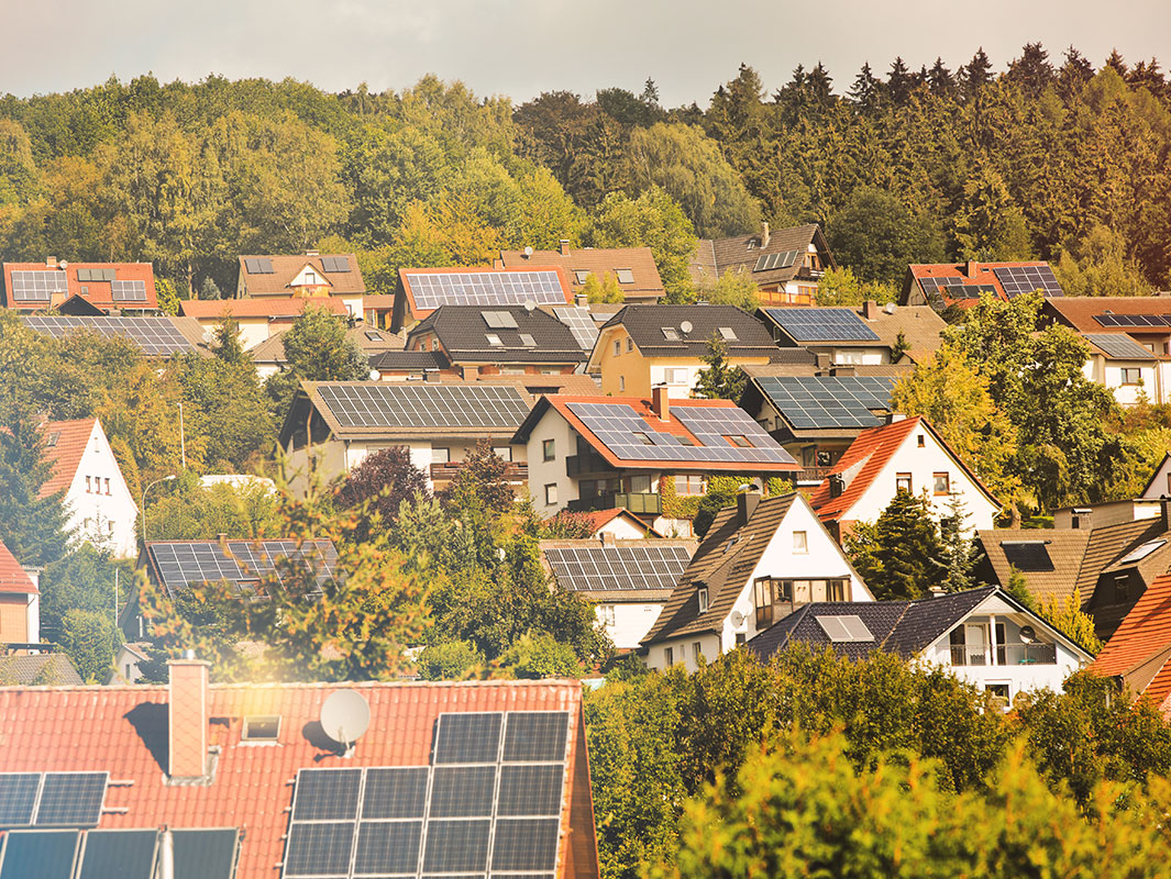 Blick auf ein Dorf oder eine Kleinstadt mit vielen Gebäuden, die Solarpaneele auf ihren Dächern haben.